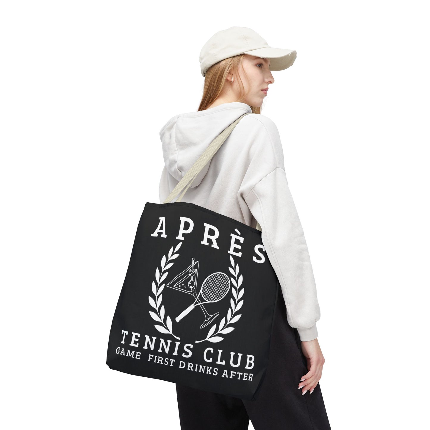 tennis tote bag Person holding a black tote bag with 'Apres Tennis Club' text and graphics on a white background