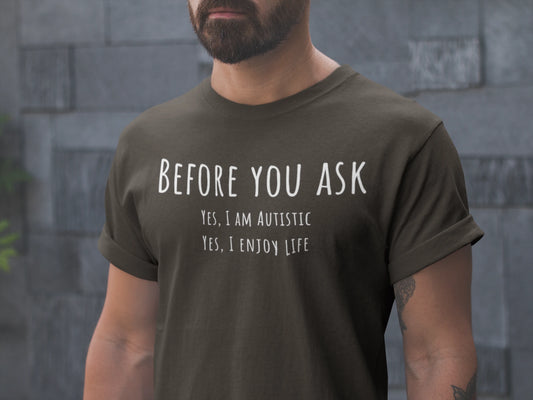 Person wearing a dark green t-shirt with text in front of a stone wall.