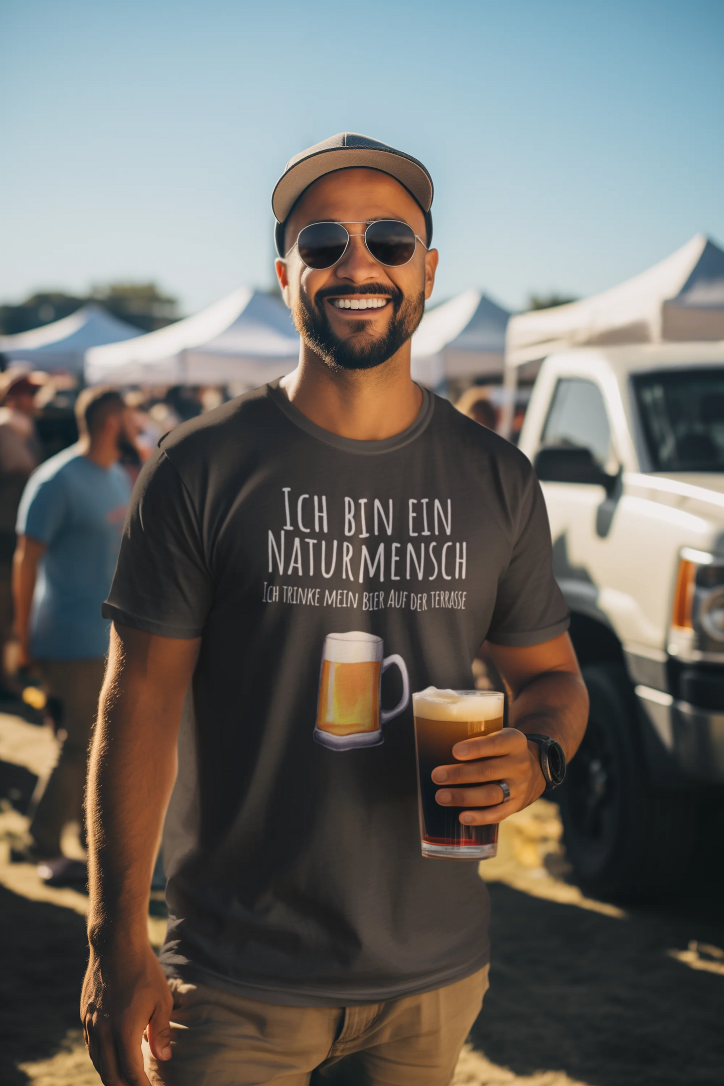 Man holding a beer mug at an outdoor event wearing a t-shirt with text and graphics.