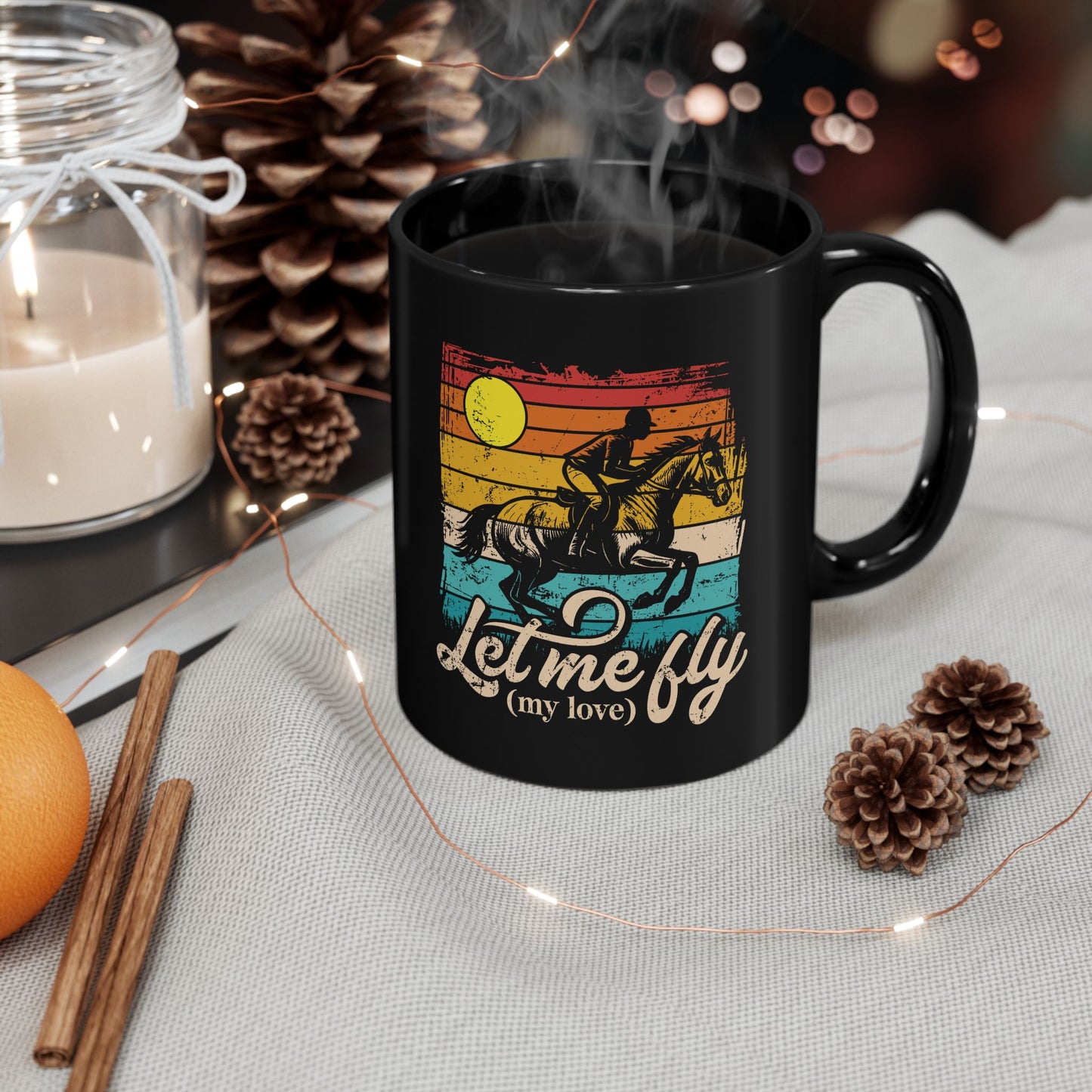 Black mug with a colorful design featuring a horse and text, surrounded by decorative items on a table.