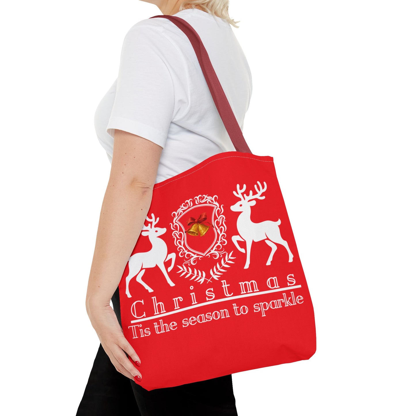 Red tote bag with Christmas design and text held by a person on a white background