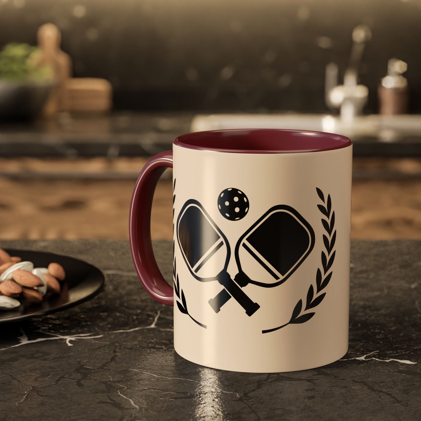 pickleball mug A ceramic mug with a cream-colored exterior and a dark red interior, featuring a black graphic of table tennis paddles, a ball, and laurel leaves. The mug is set on a dark marble countertop with a blurred kitchen background.