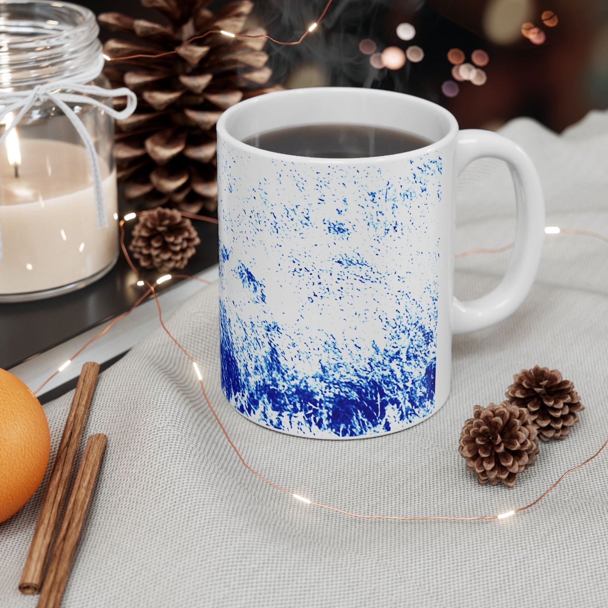 White mug with blue speckled design on a table with decorative items