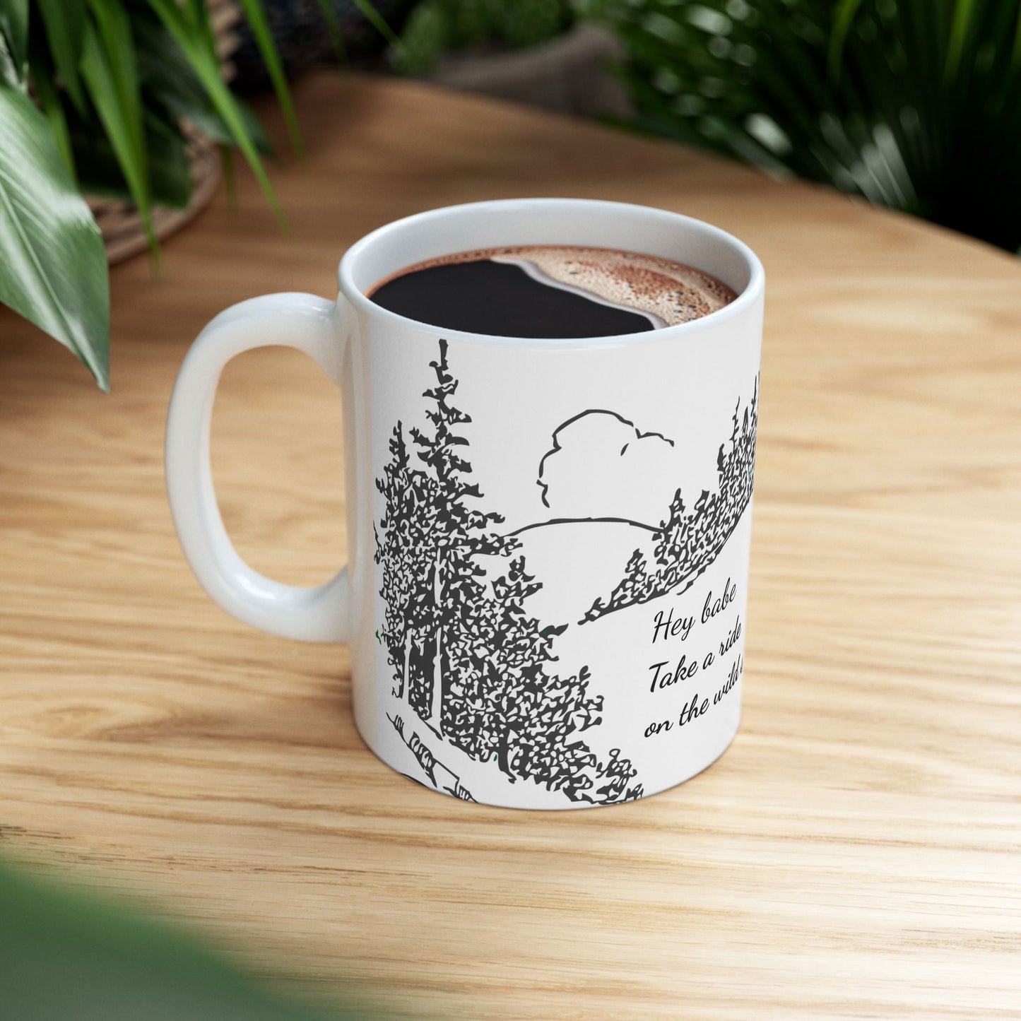 White mug with nature-themed design on a wooden table