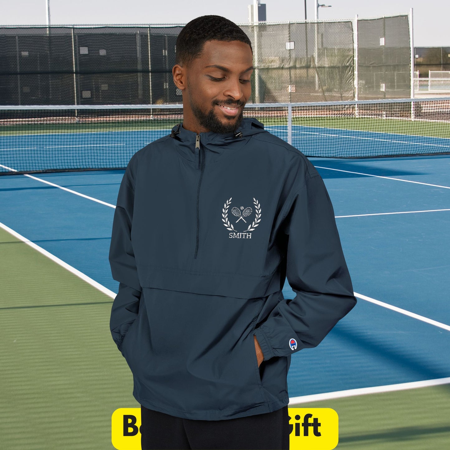 vMan wearing a navy blue jacket with a logo on a tennis court
