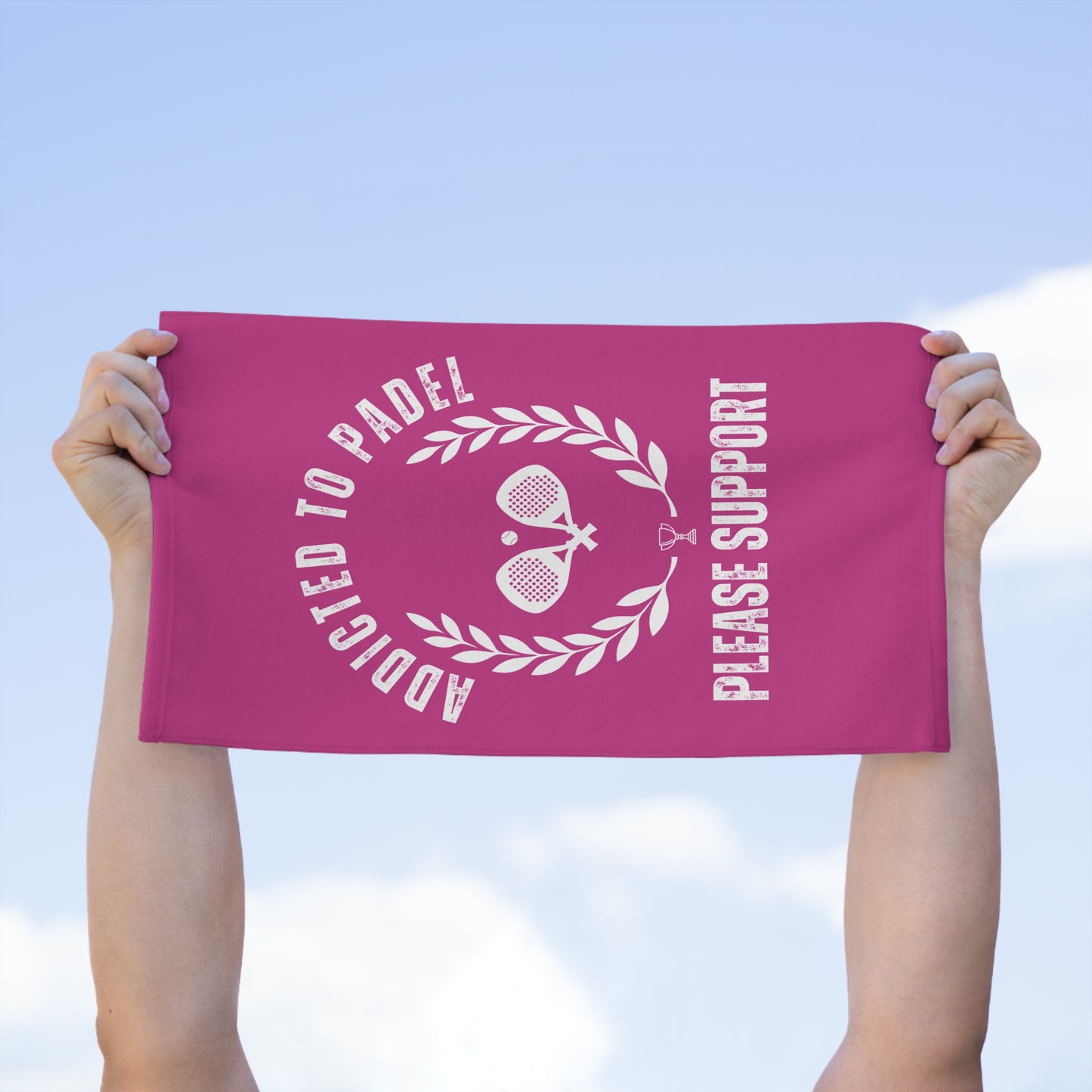 Pink towel with white text and graphics held up against a blue sky