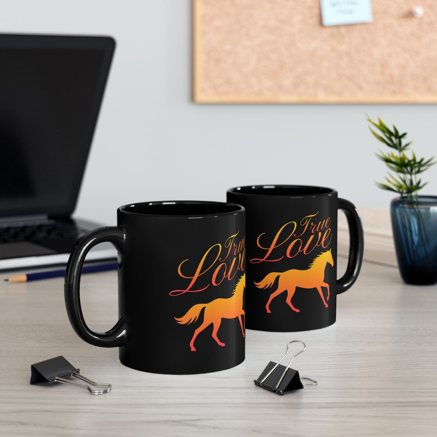 Two black mugs with 'True Love' and horse design on a desk with office items.