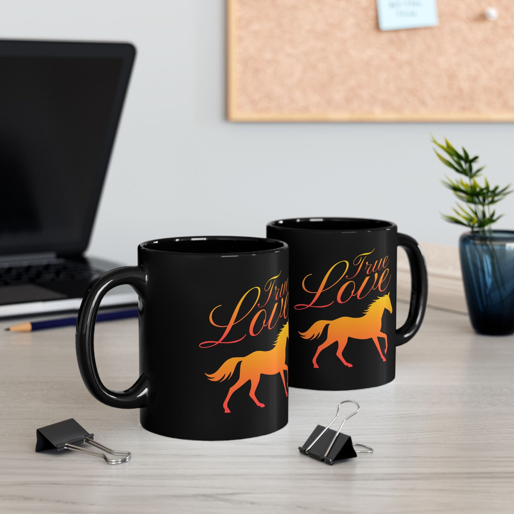 Two black mugs with 'True Love' and horse design on a desk with office items.