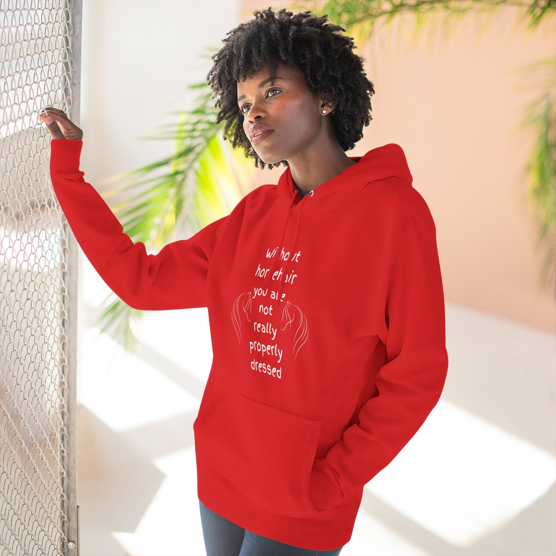 Person wearing a red hoodie with text and graphics, standing indoors with plants in the background