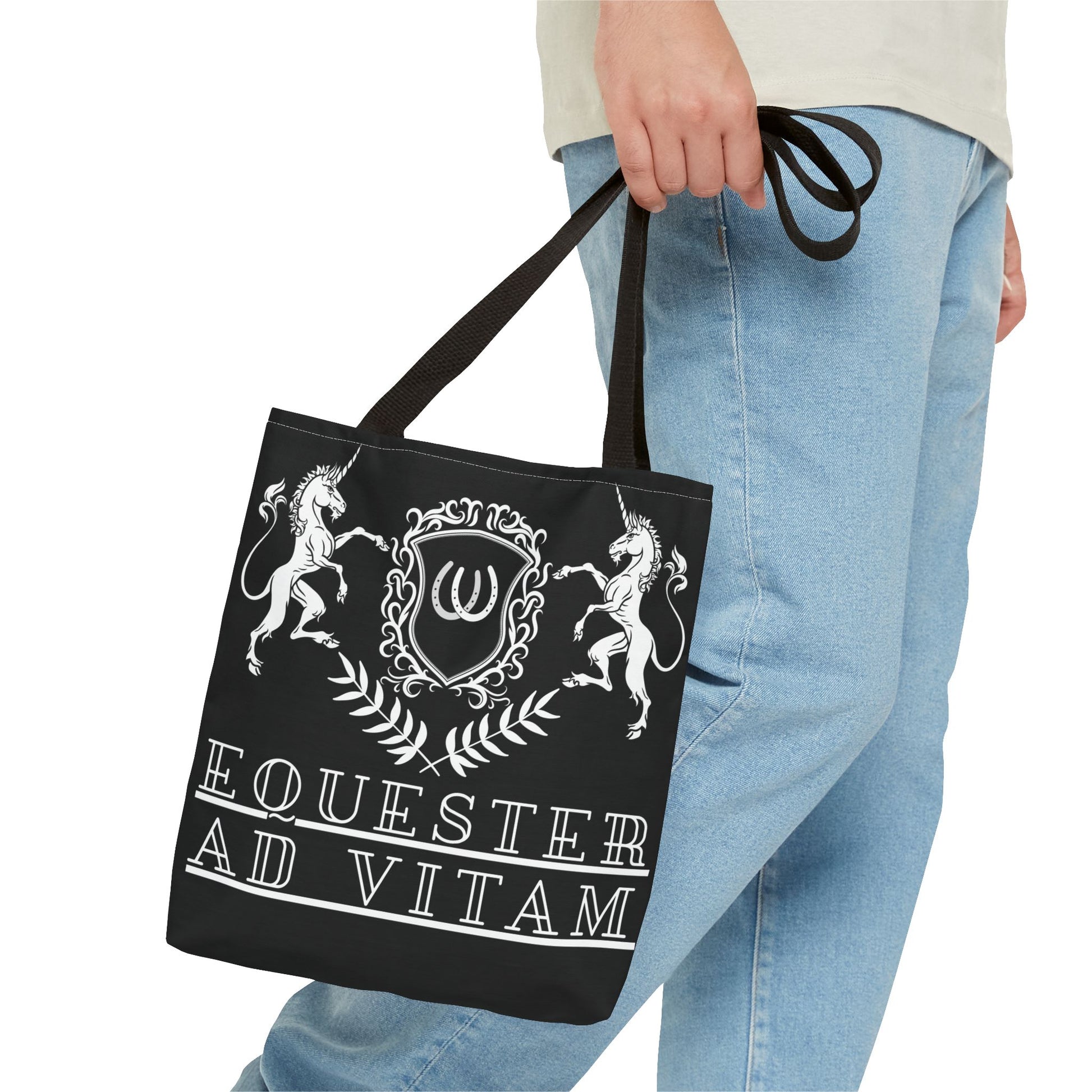Black tote bag with white design and text held by a person wearing light blue jeans.