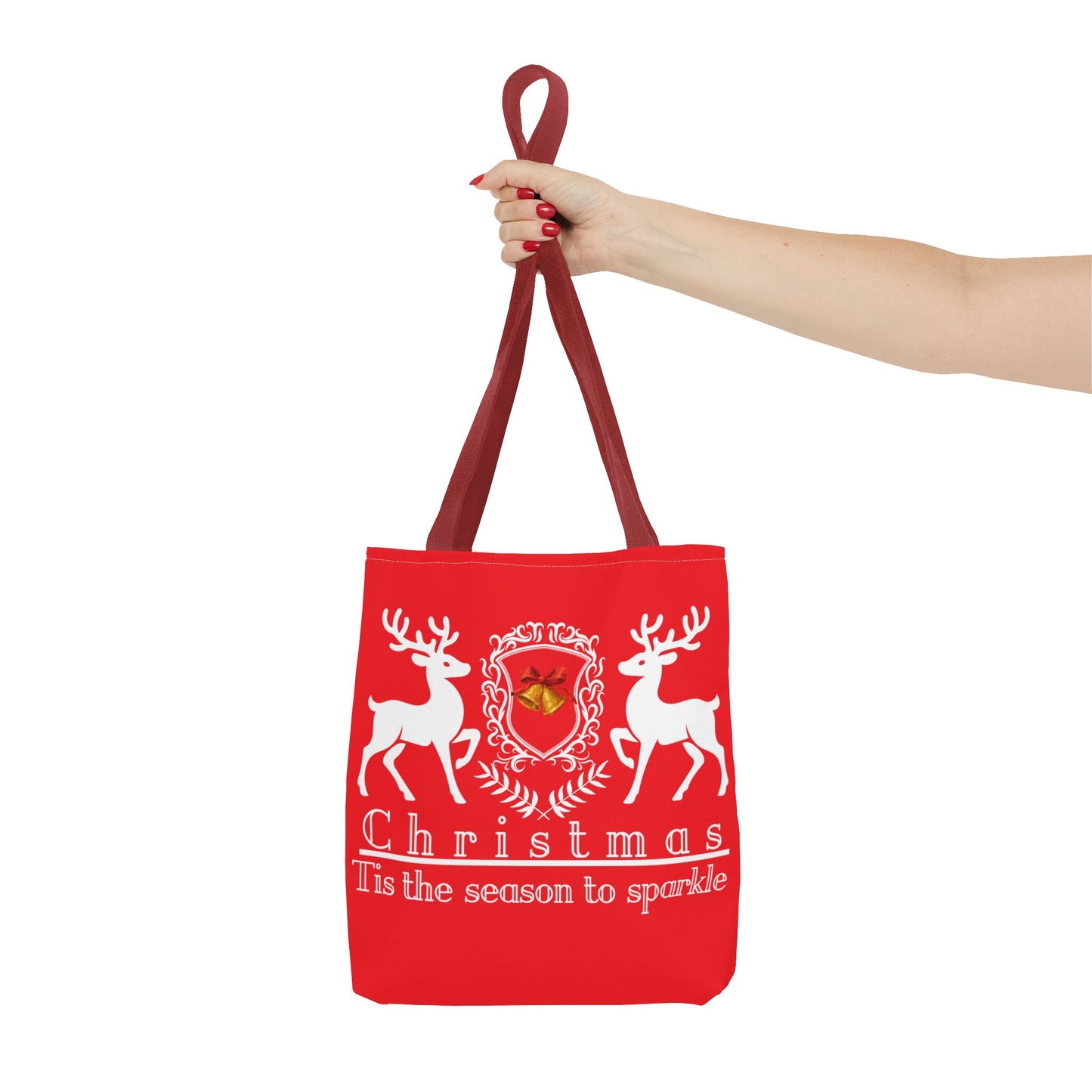 Red tote bag with reindeer design and text held by a hand on a white background