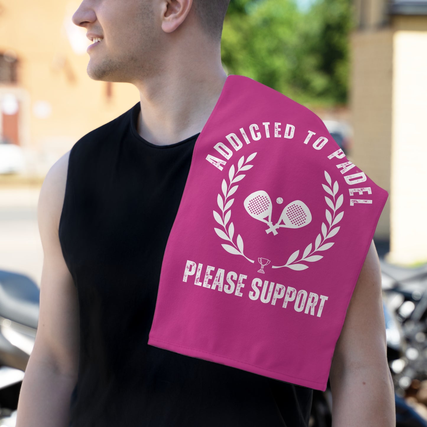Person holding a pink towel with 'Addicted to Padel Please Support' text and tennis racket design.
