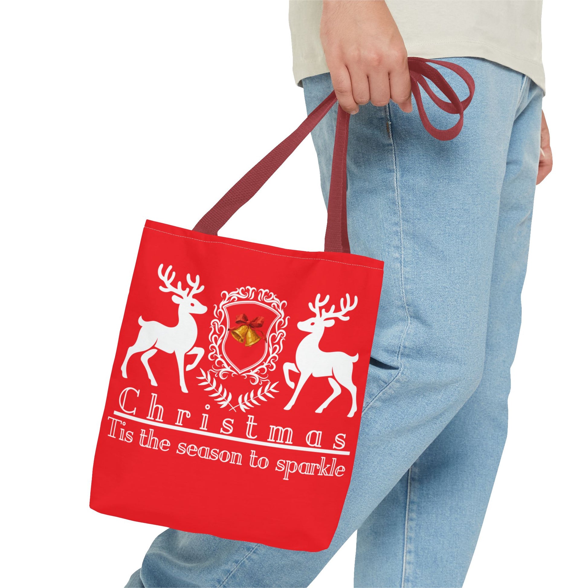 Red tote bag with Christmas design held by a person wearing blue jeans.