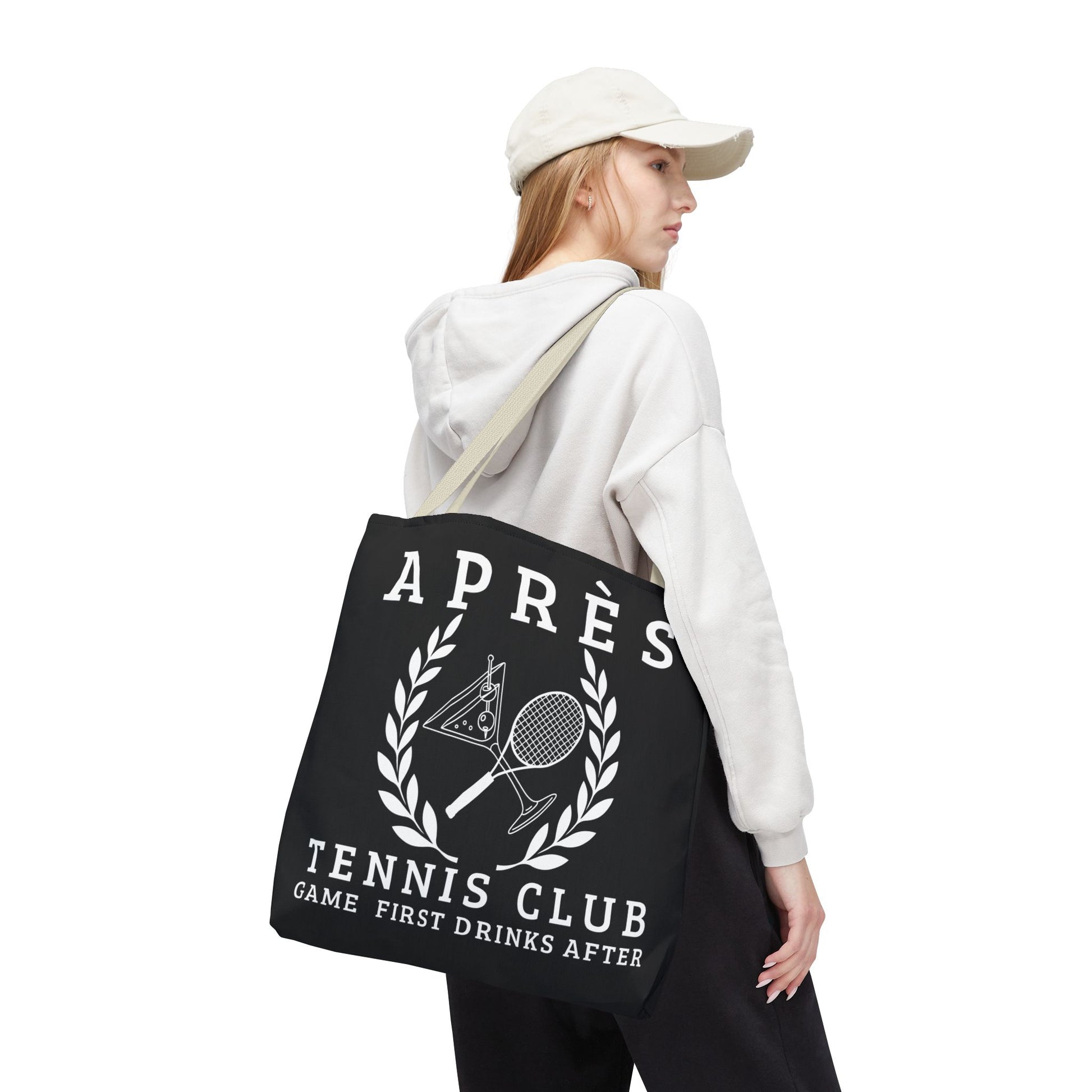 tennis tote bag Person holding a black tote bag with 'Apres Tennis Club' text and graphics on a white background
