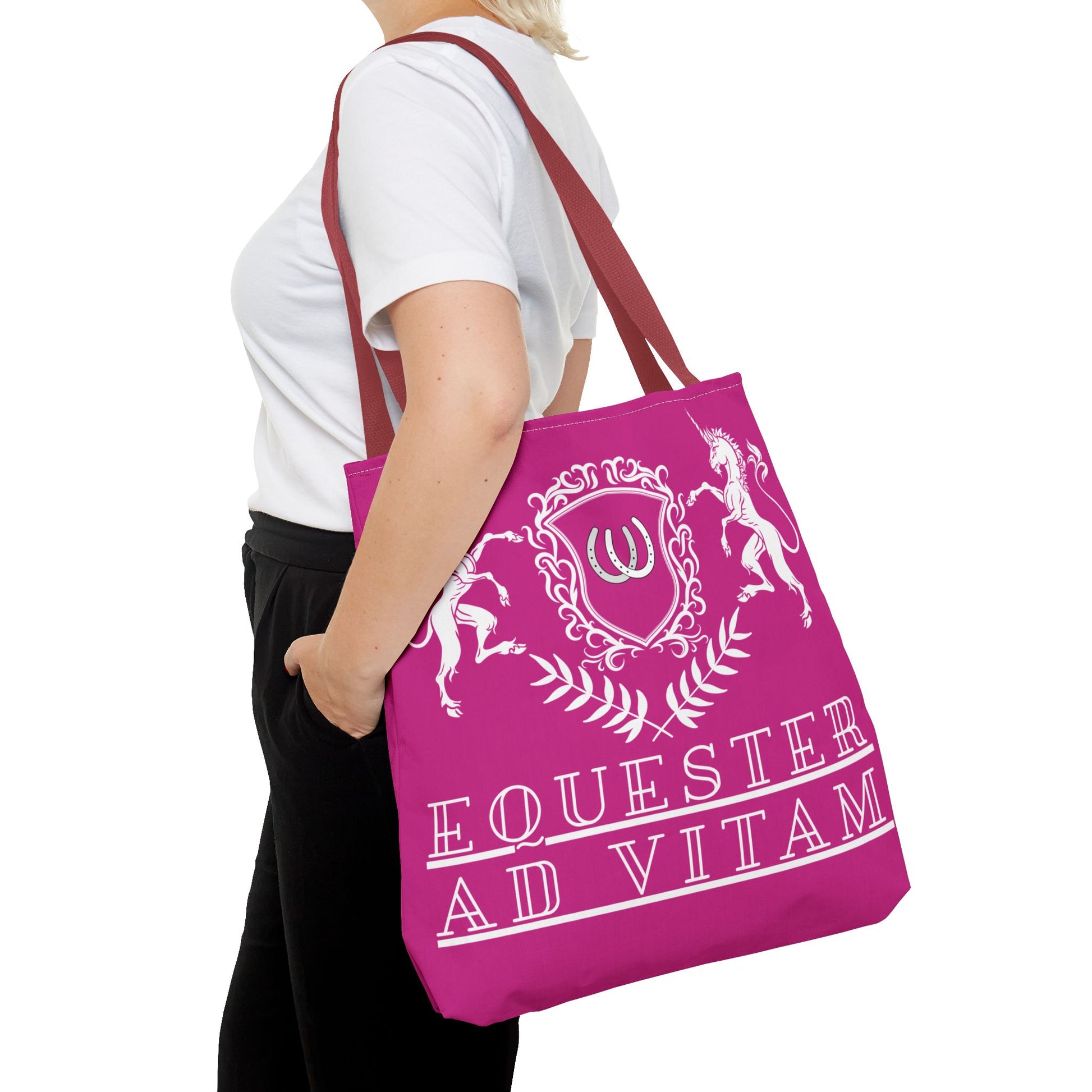 Person holding a pink tote bag with white text and design on a white background