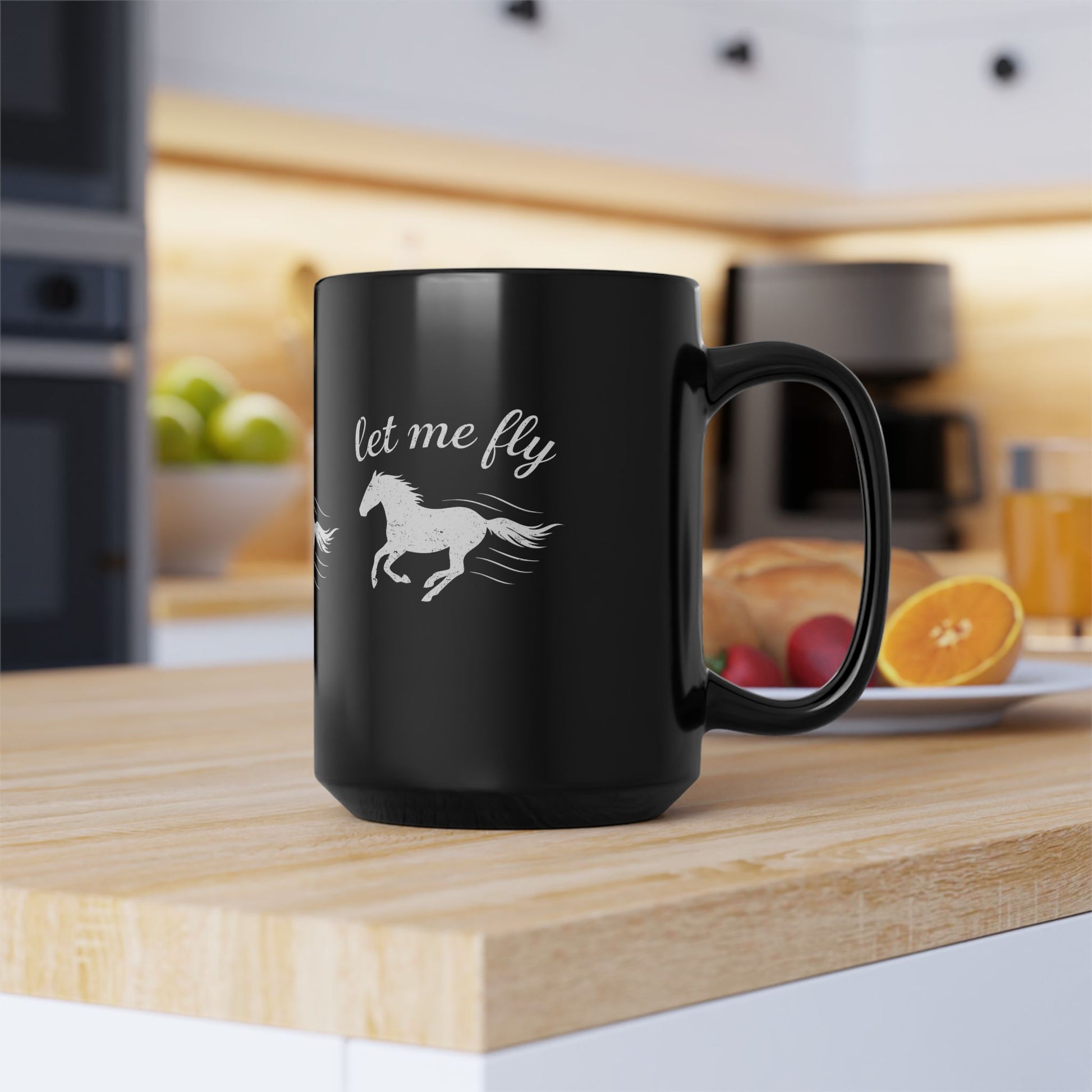 Black mug with horse design and 'let me fly' text on a kitchen counter.