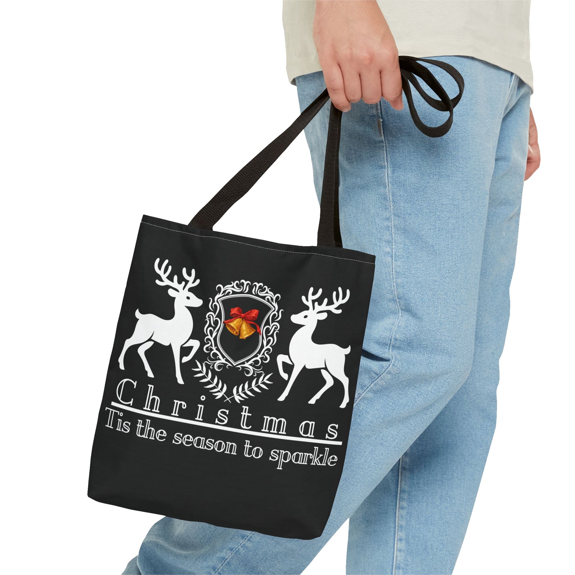 Black tote bag with Christmas design held by a person wearing blue jeans.