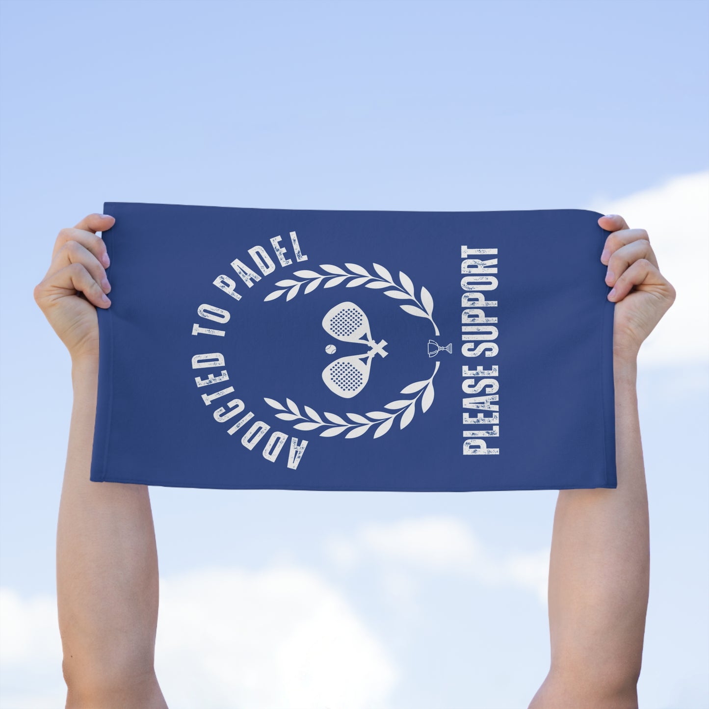 Person holding a blue towel with white text and graphics against a clear sky