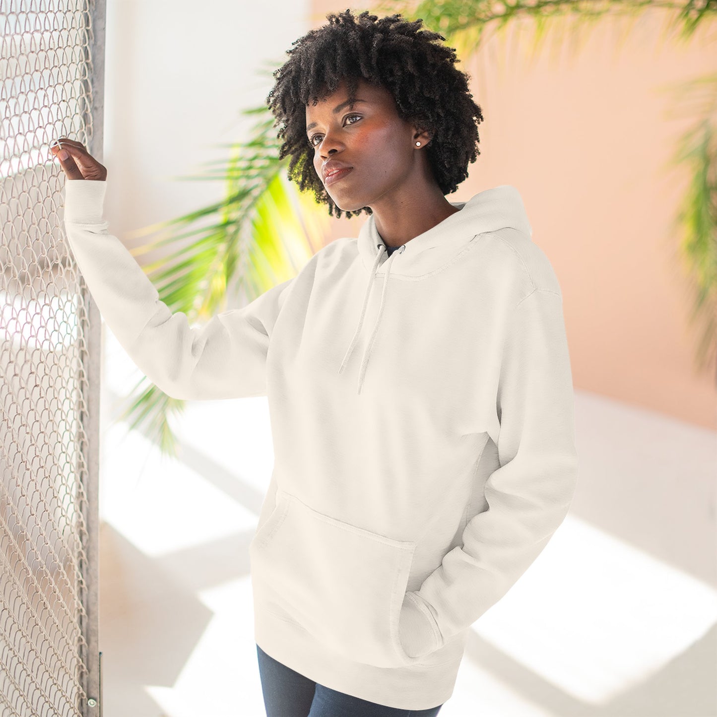 Tennis Hoodie Person wearing a white hoodie standing against a light background with plants.