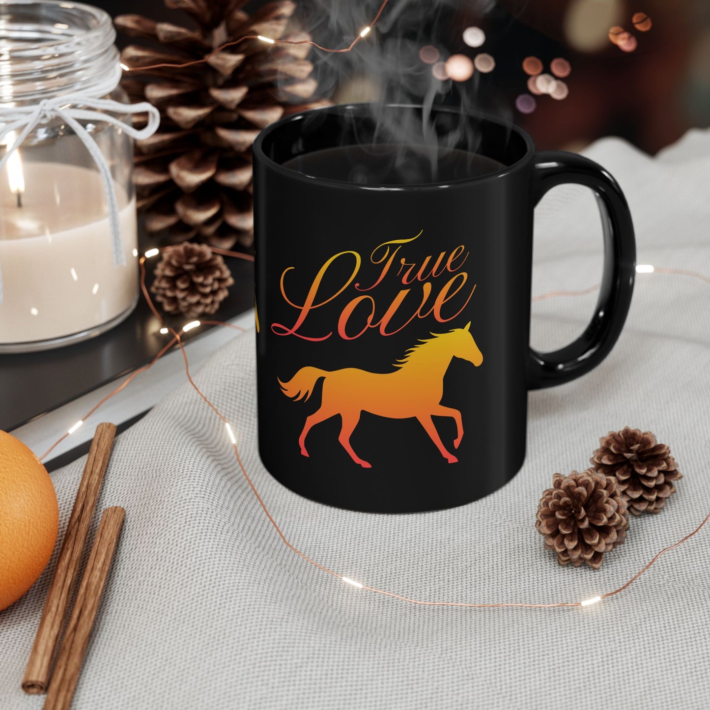 Black mug with 'True Love' and horse design, surrounded by decorative items on a table.