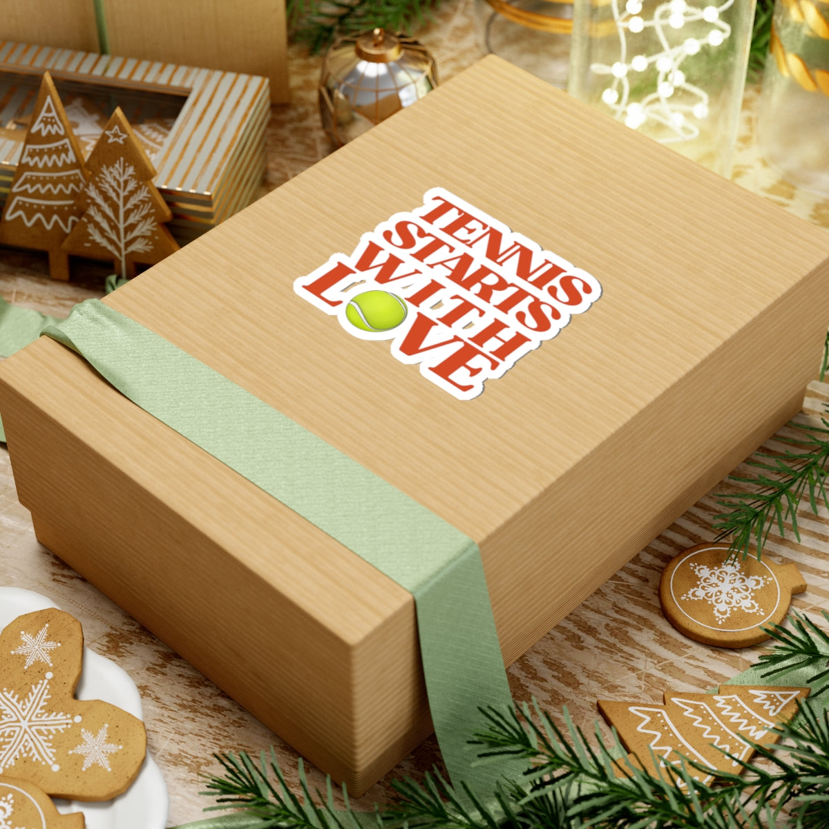 Wooden gift box with 'Tennis Starts with Love' sticker on a festive background with cookies and decorations.