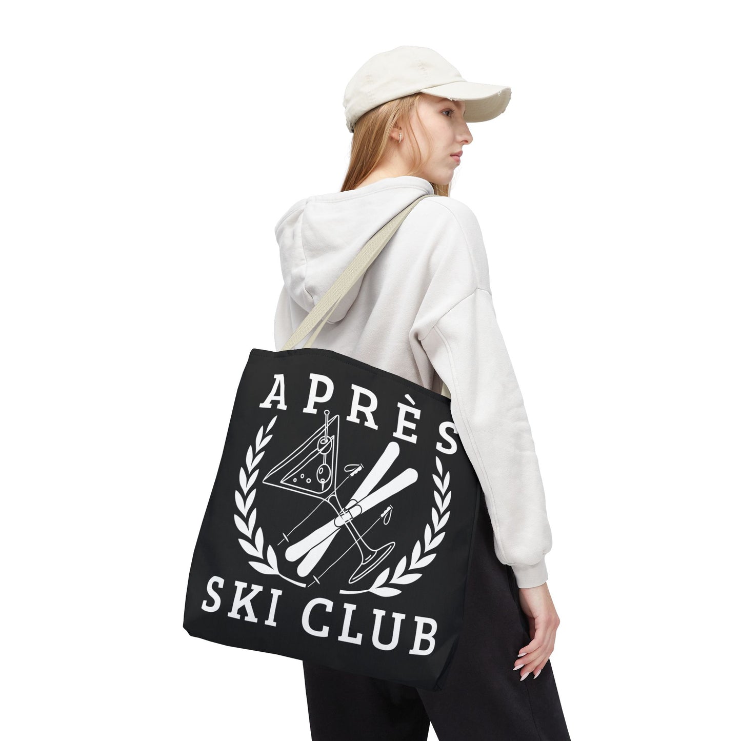 ski tote bag Person wearing a white hoodie and black pants with a black tote bag featuring 'Ap
es Ski Club' text and design.