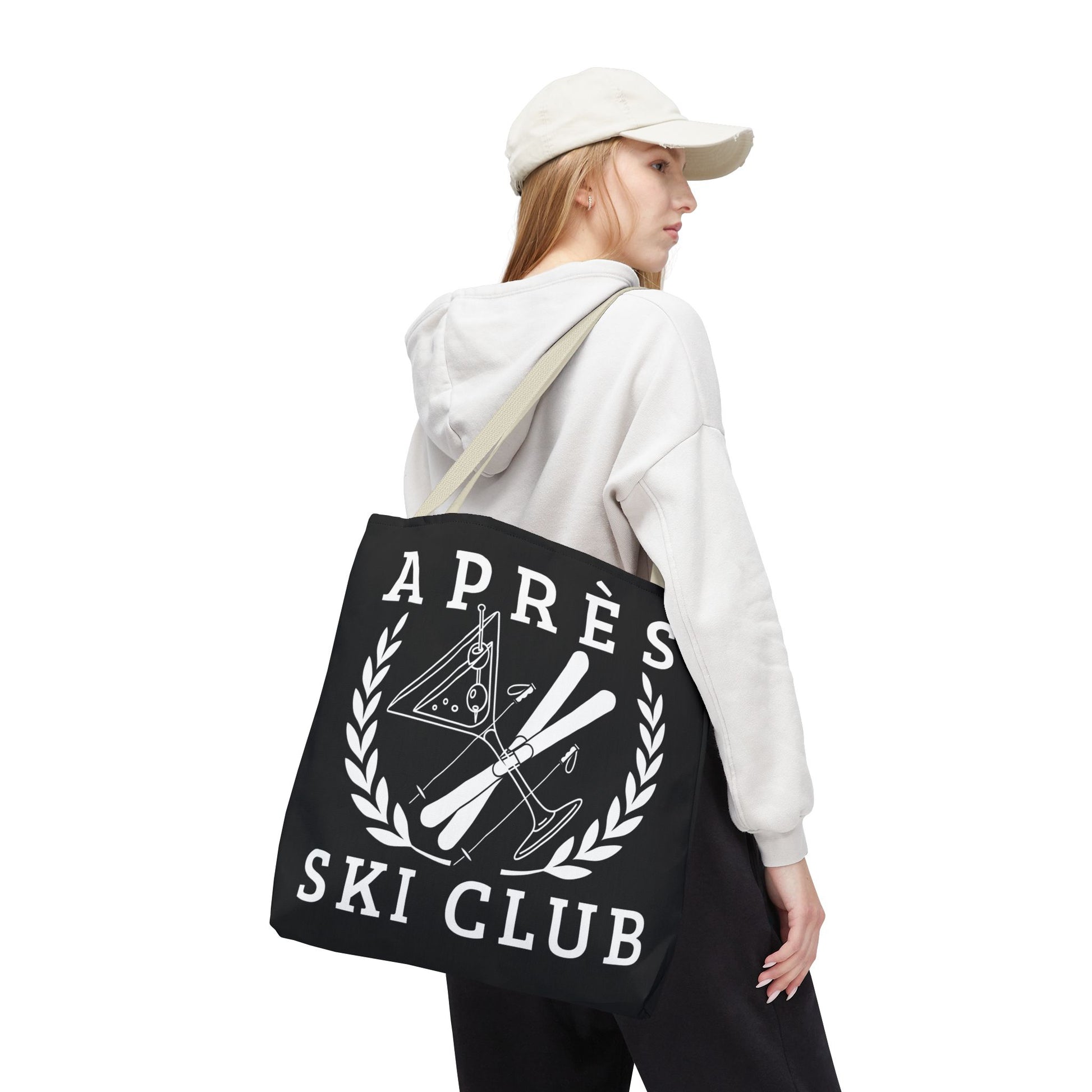 ski tote bag Person wearing a white hoodie and black pants with a black tote bag featuring 'Ap
es Ski Club' text and design.