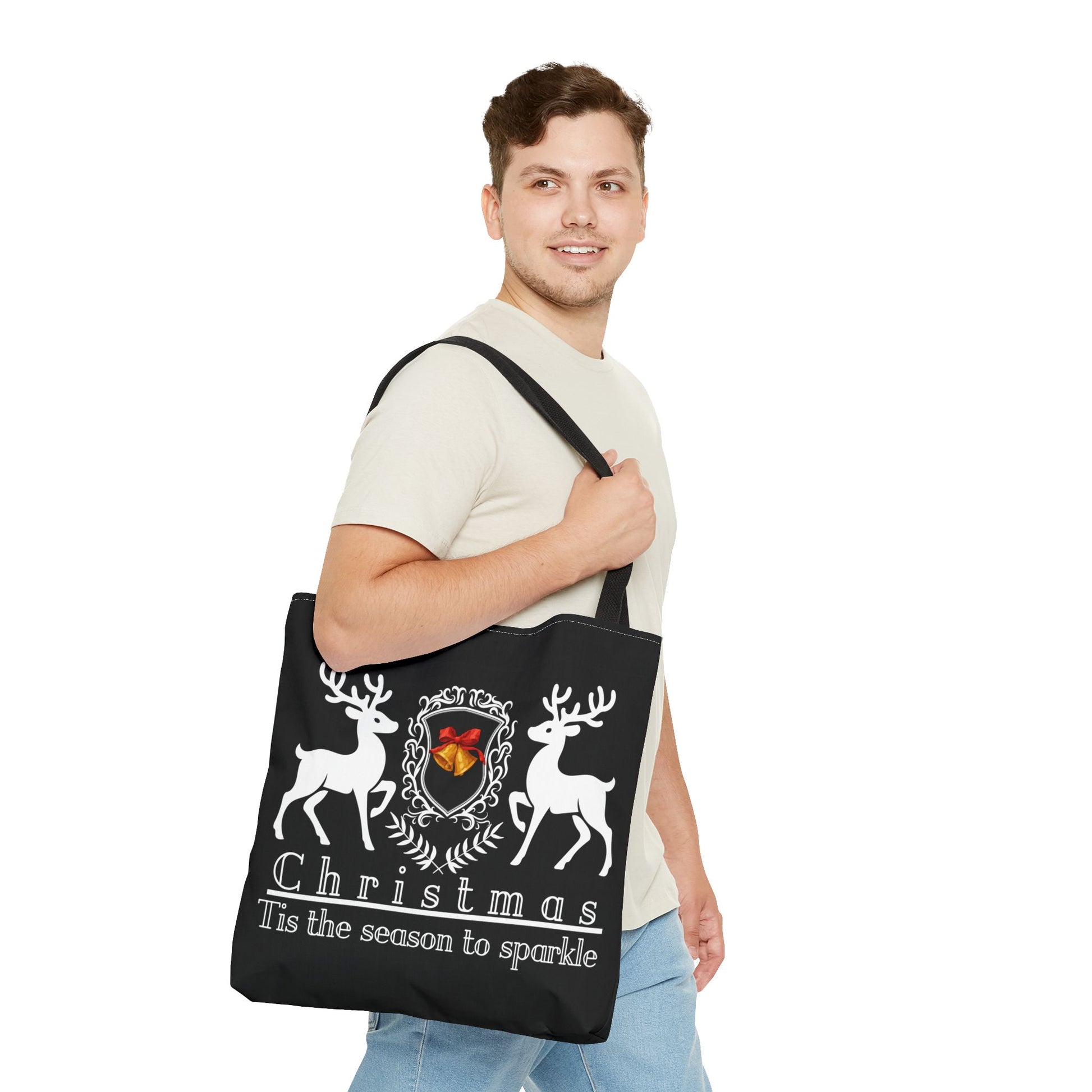 Man holding a black tote bag with Christmas design and text.