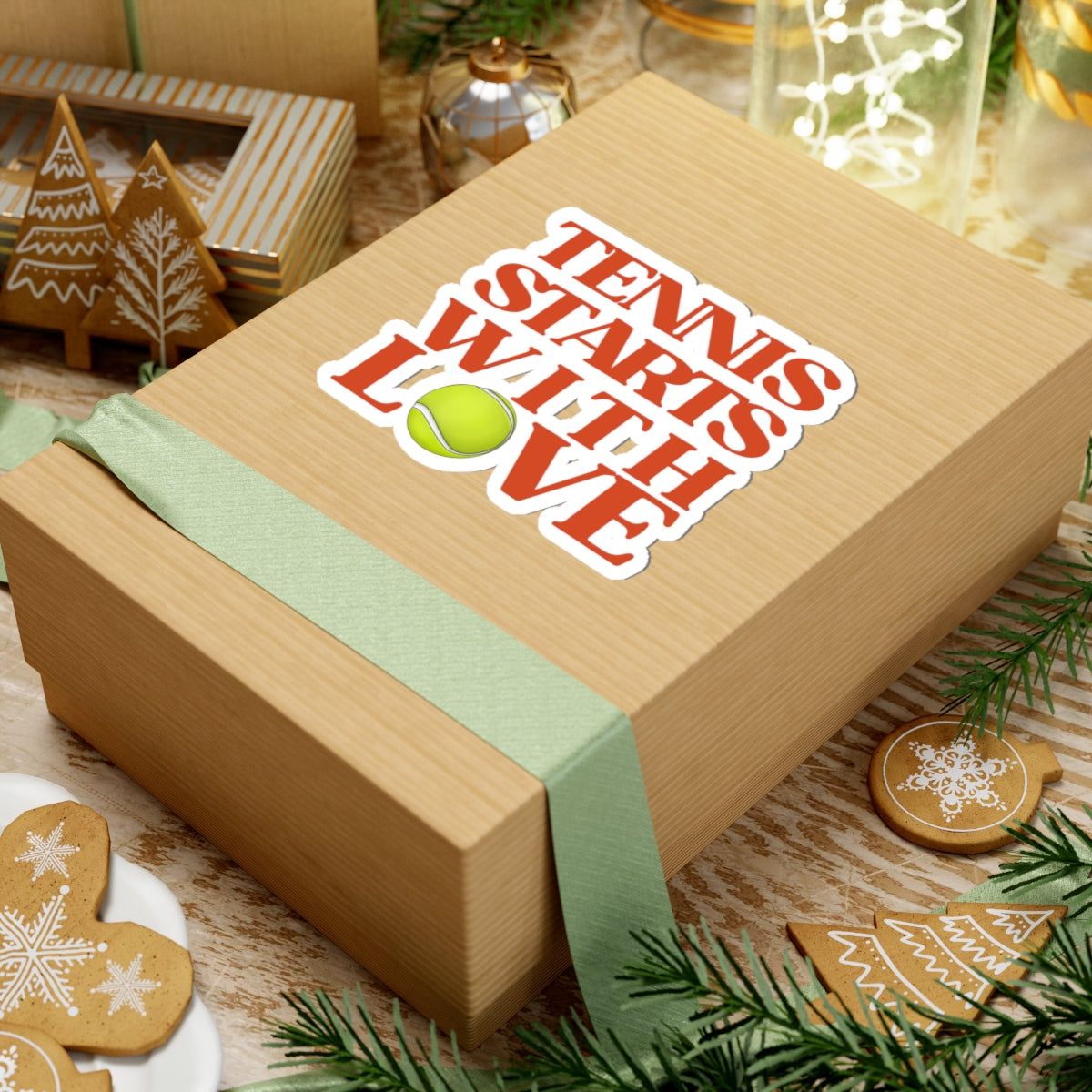Wooden gift box with 'Tennis Starts with Love' text and tennis ball graphic, surrounded by festive decorations.