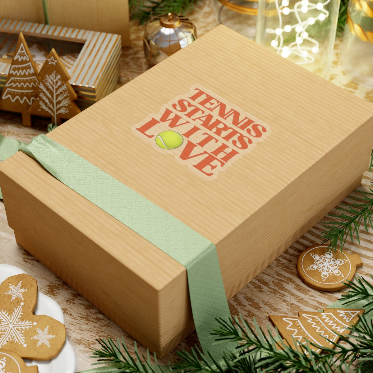 Wooden gift box with 'Tennis Starts with Love' text and tennis ball graphic, surrounded by Christmas decorations.