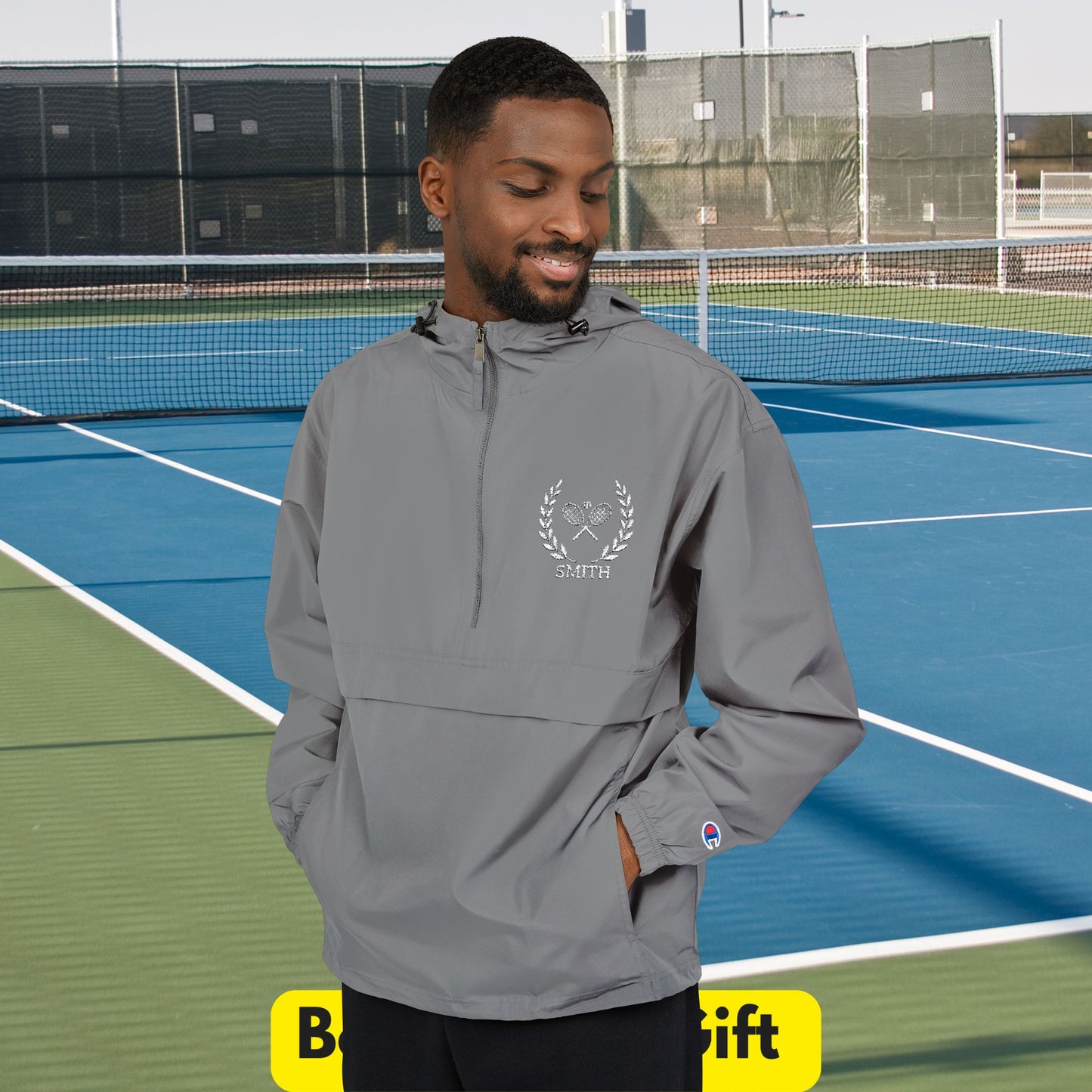 Tennis jacket Man wearing a gray hoodie with a logo on a tennis court