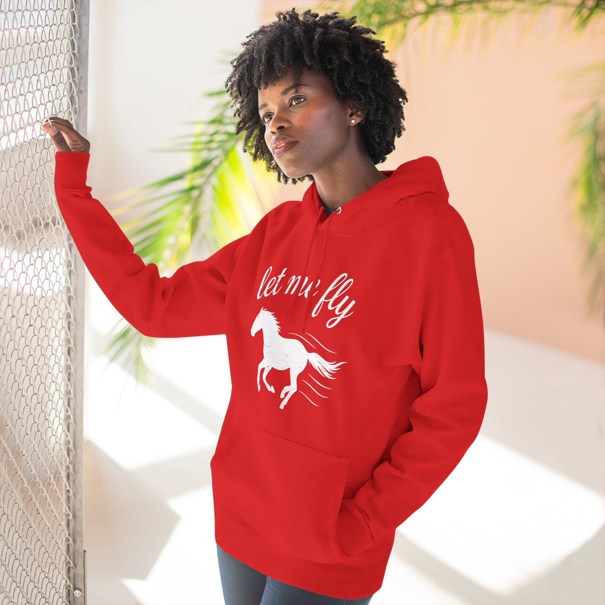 Person wearing a red hoodie with a horse graphic and text, standing indoors.