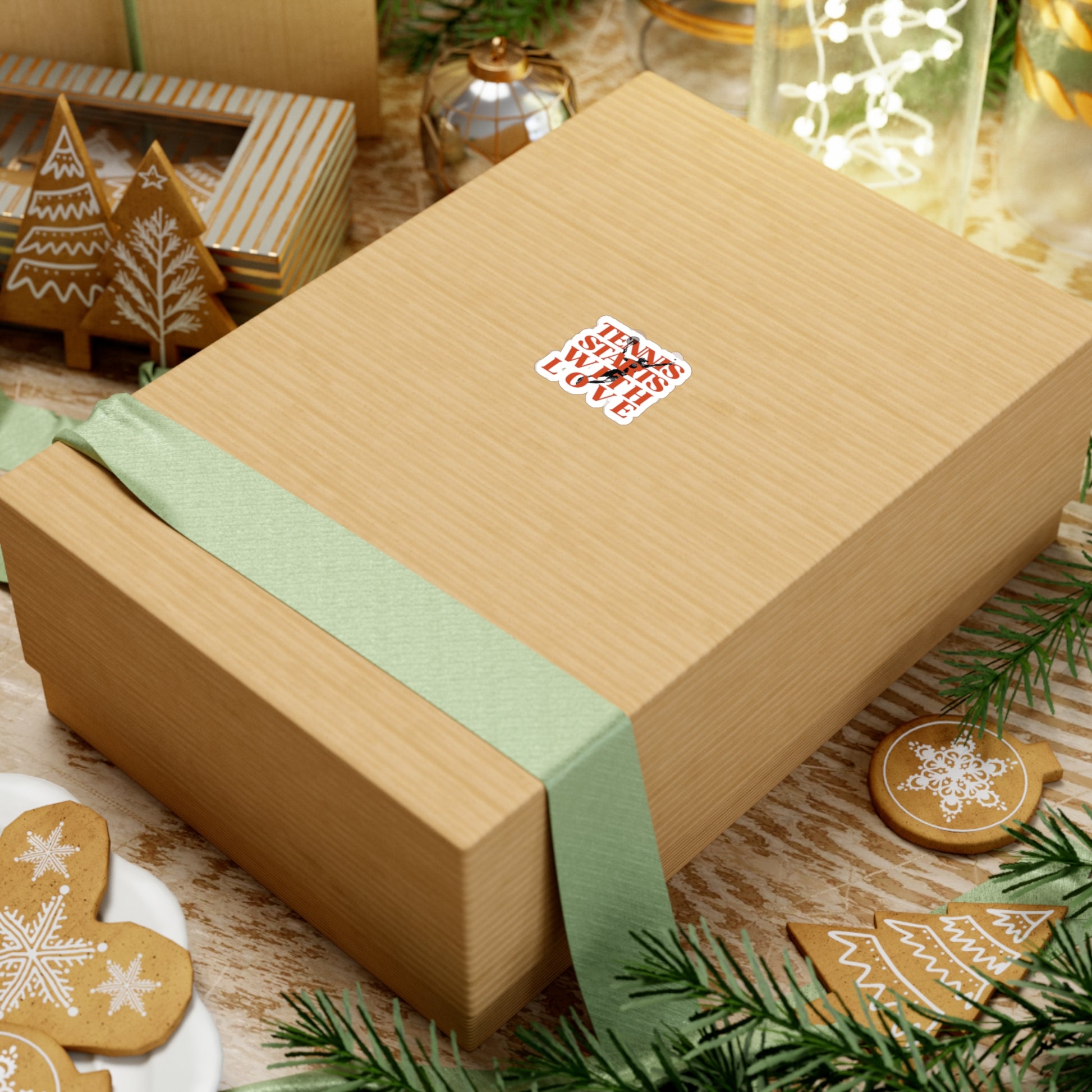 Gift box with a green ribbon on a festive background with cookies and lights