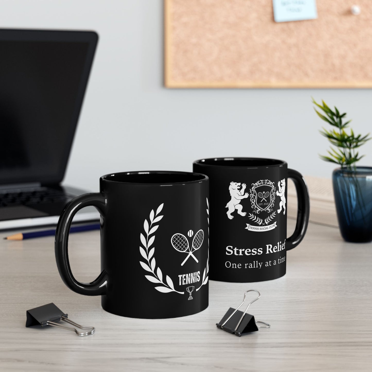 Tennis Mug Two black mugs with white designs on a desk with office supplies and a plant.