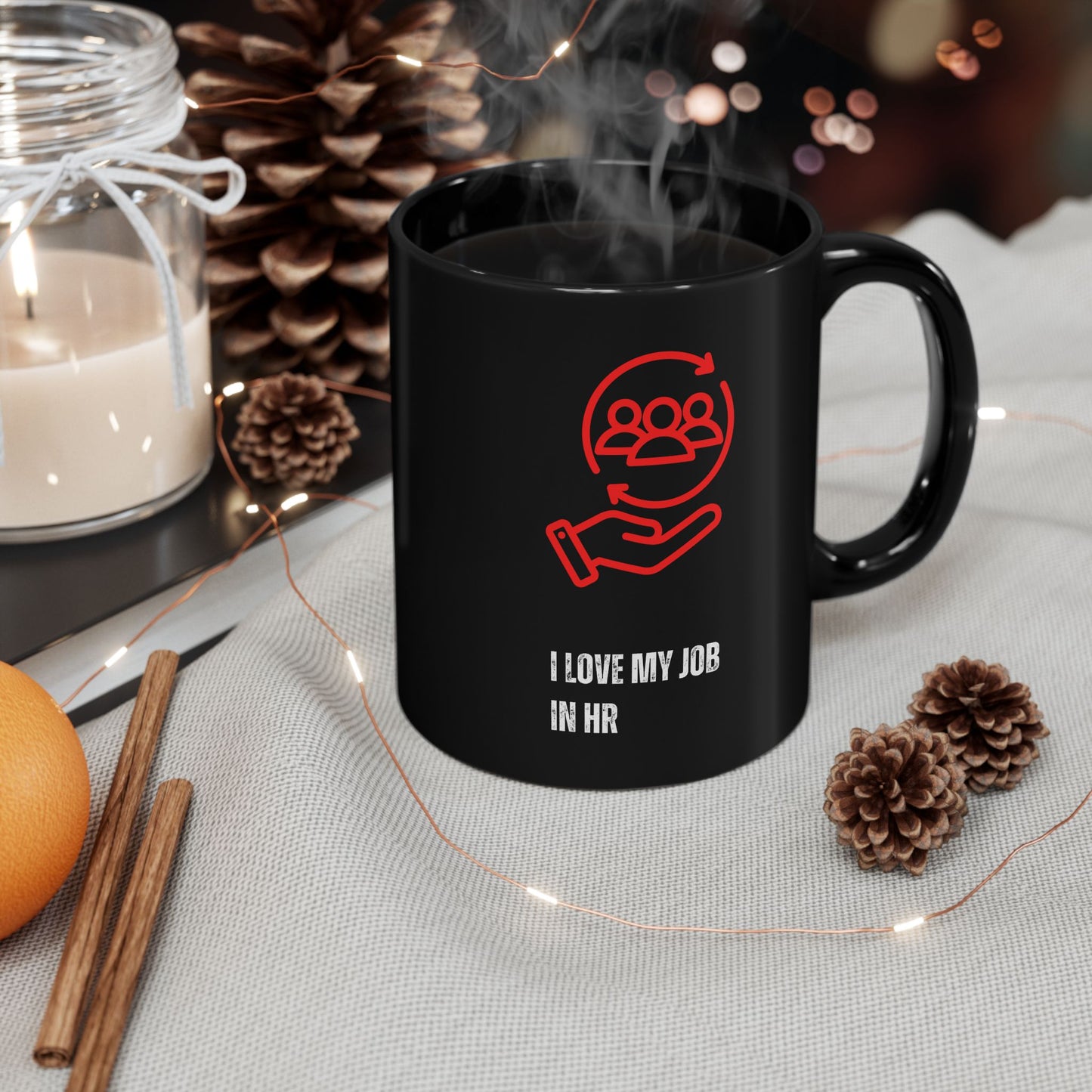 HR Coffee Mug Black mug with red graphic and text 'I love my job in HR' on a table with decorative items.