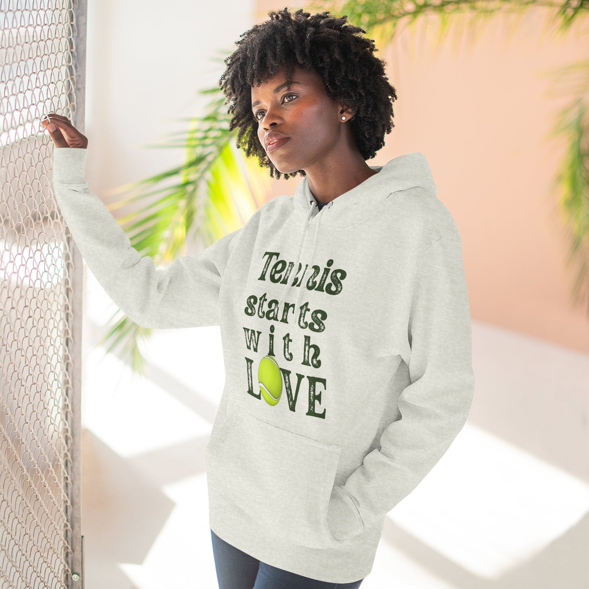 Person wearing a hoodie with 'Tennis starts with LOVE' text and a tennis ball graphic.