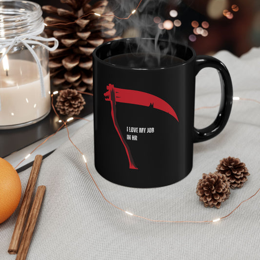 Black mug with a red Grim Reaper design and text, surrounded by decorative items on a table.