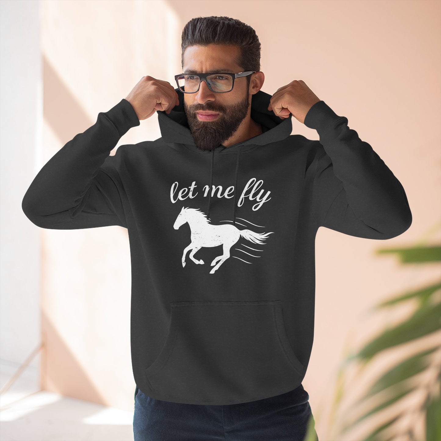 Man wearing a black hoodie with a horse graphic and 'let me fly' text.