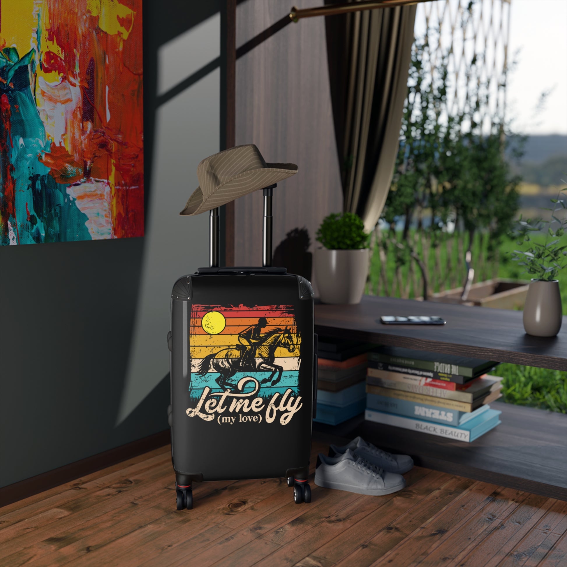 Black suitcase with a colorful design and text in a room with books and a hat.