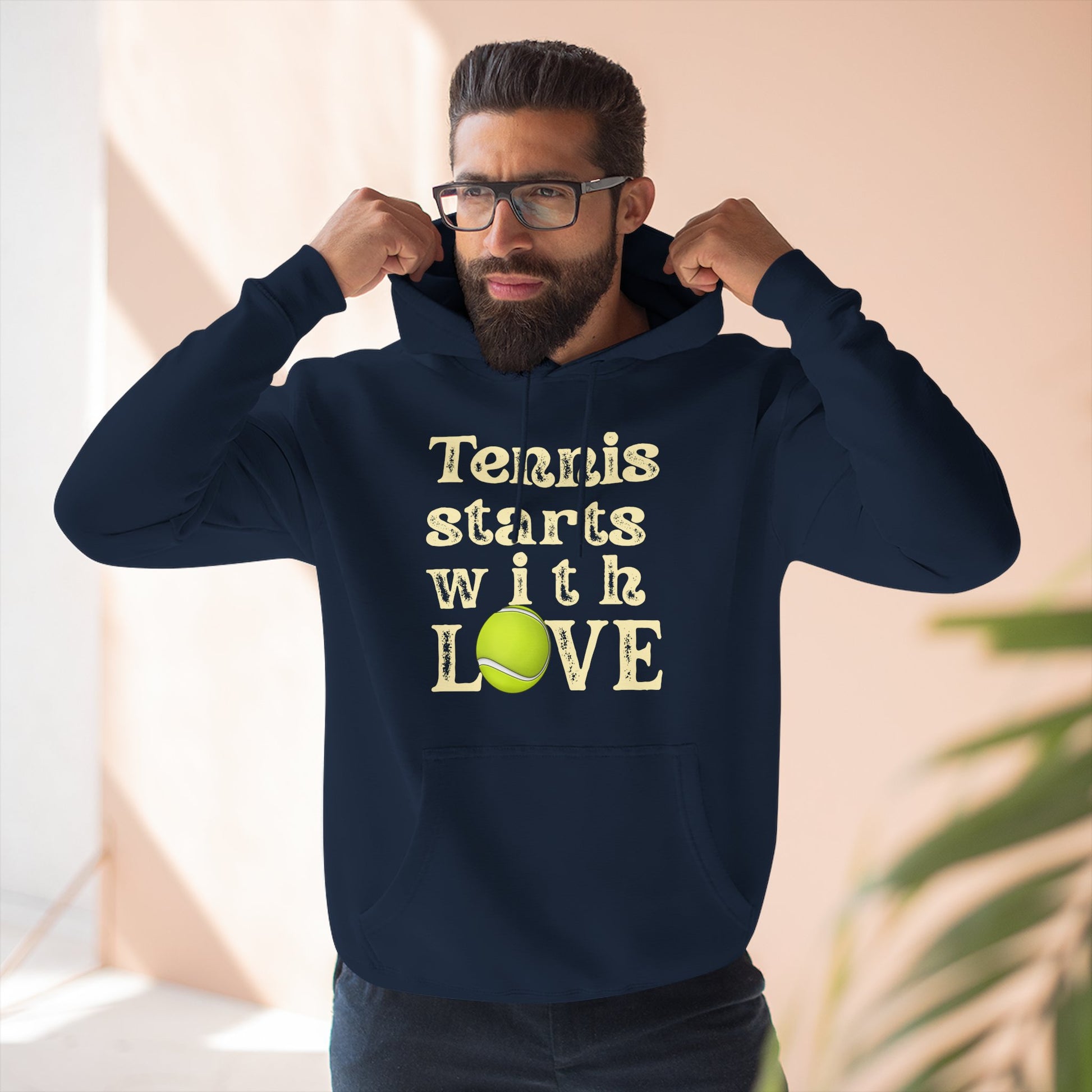 Man wearing a navy hoodie with 'Tennis starts with LOVE' text and tennis ball graphic.