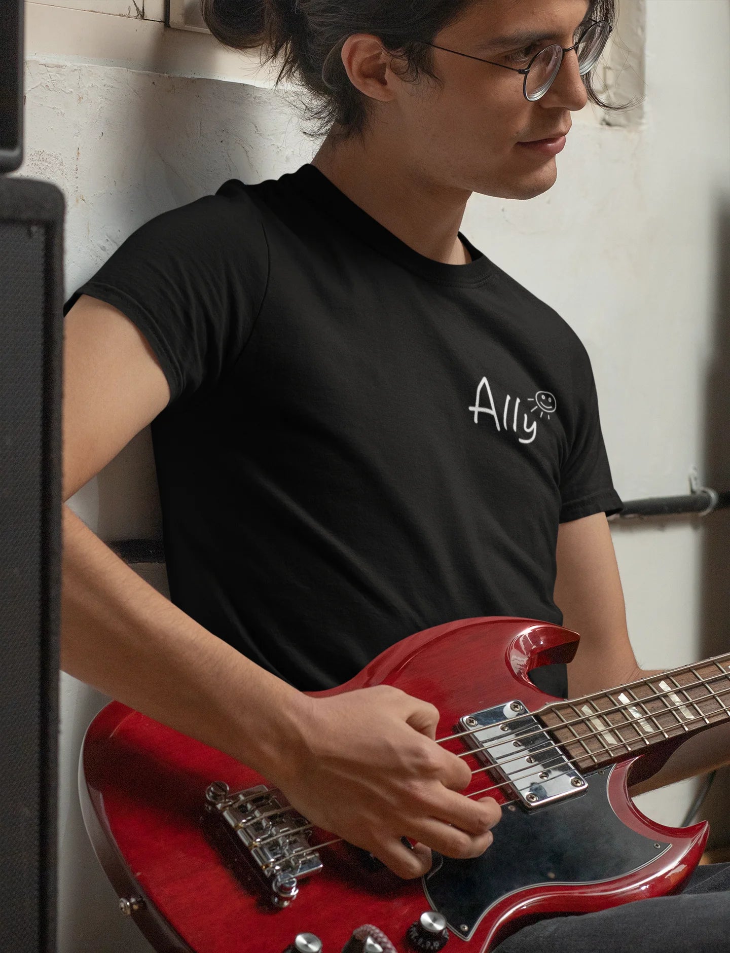 Ally music band Shirt Person playing a red electric guitar with a black t-shirt featuring a logo.