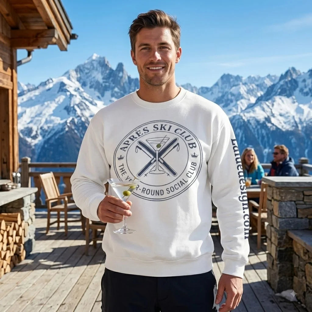 Après Ski Sweatshirt A man wearing a white crewneck sweatshirt with a circular 'Après Ski Club' graphic on the chest and 'launchesiq.com' printed down the sleeve, standing on a wooden deck with a snowy mountain background.