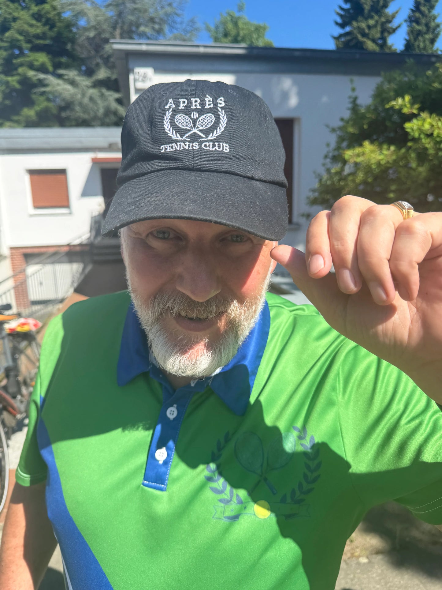 Tennis Cap Man wearing a green and blue polo shirt with a cap outdoors