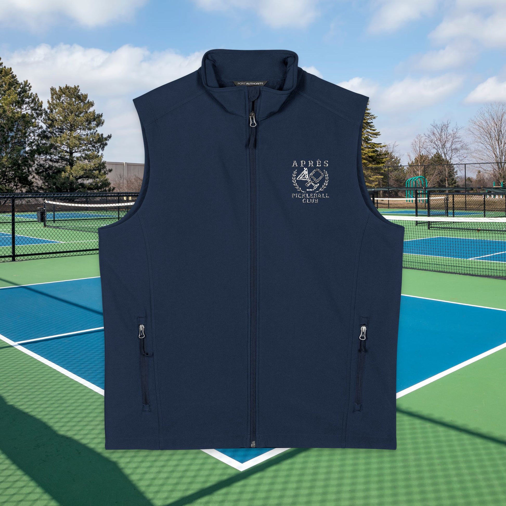 Apres pickleball vest A black sleeveless zip-front vest with a stand collar and two vertical zip pockets, shown against an outdoor tennis court background. The left chest has a white printed logo reading ARKES TENNIS CLUB.