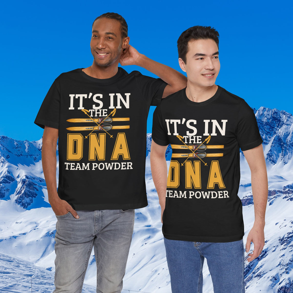 Its in the DNA Two men modeling matching black graphic t-shirts with the text 'IT'S IN THE DNA TEAM POWDER' in white and gold, set against a snowy mountain background.
