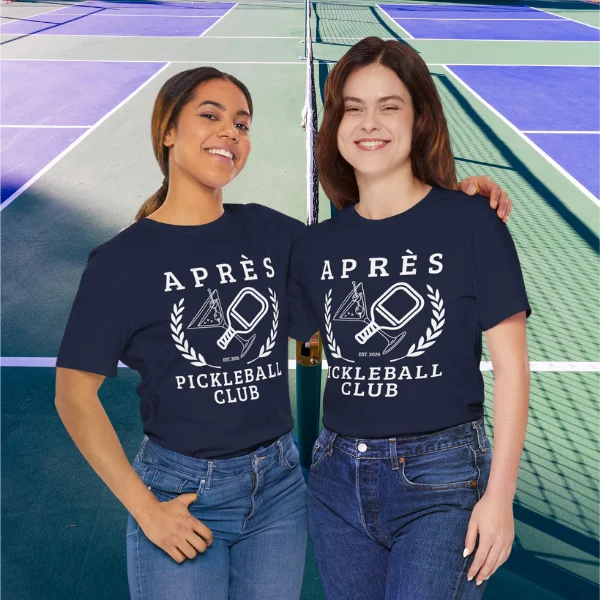 Funny Pickleball Shirt Two women wearing 'APRèS Pickleball Club' t-shirts on a pickleball court background.