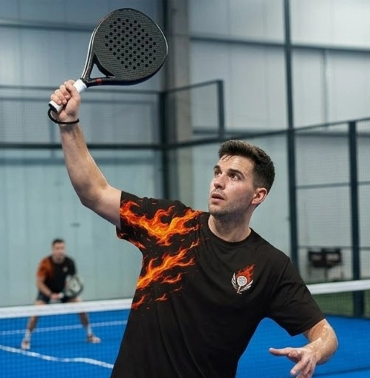 Performance Padel Shirt Man playing padel with a flaming design on his shirt in an indoor court.