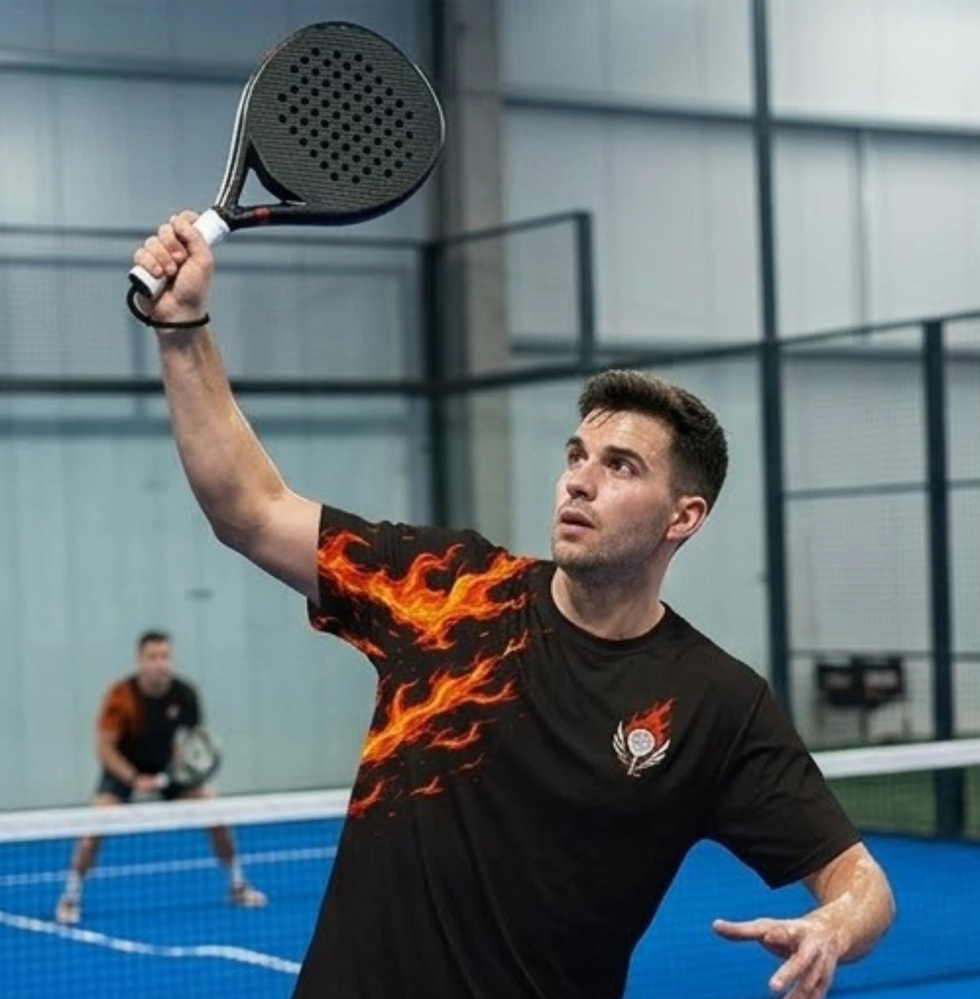 Performance Padel Shirt Man playing padel with a flaming design on his shirt in an indoor court.