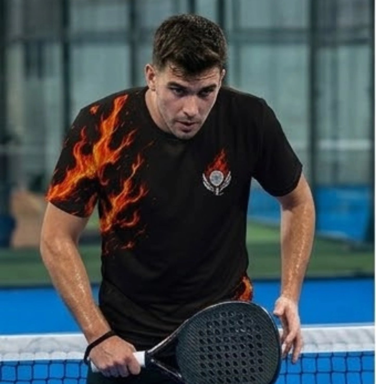 Performance Padel Shirt Man playing paddle tennis on a court with a black t-shirt featuring flame designs.