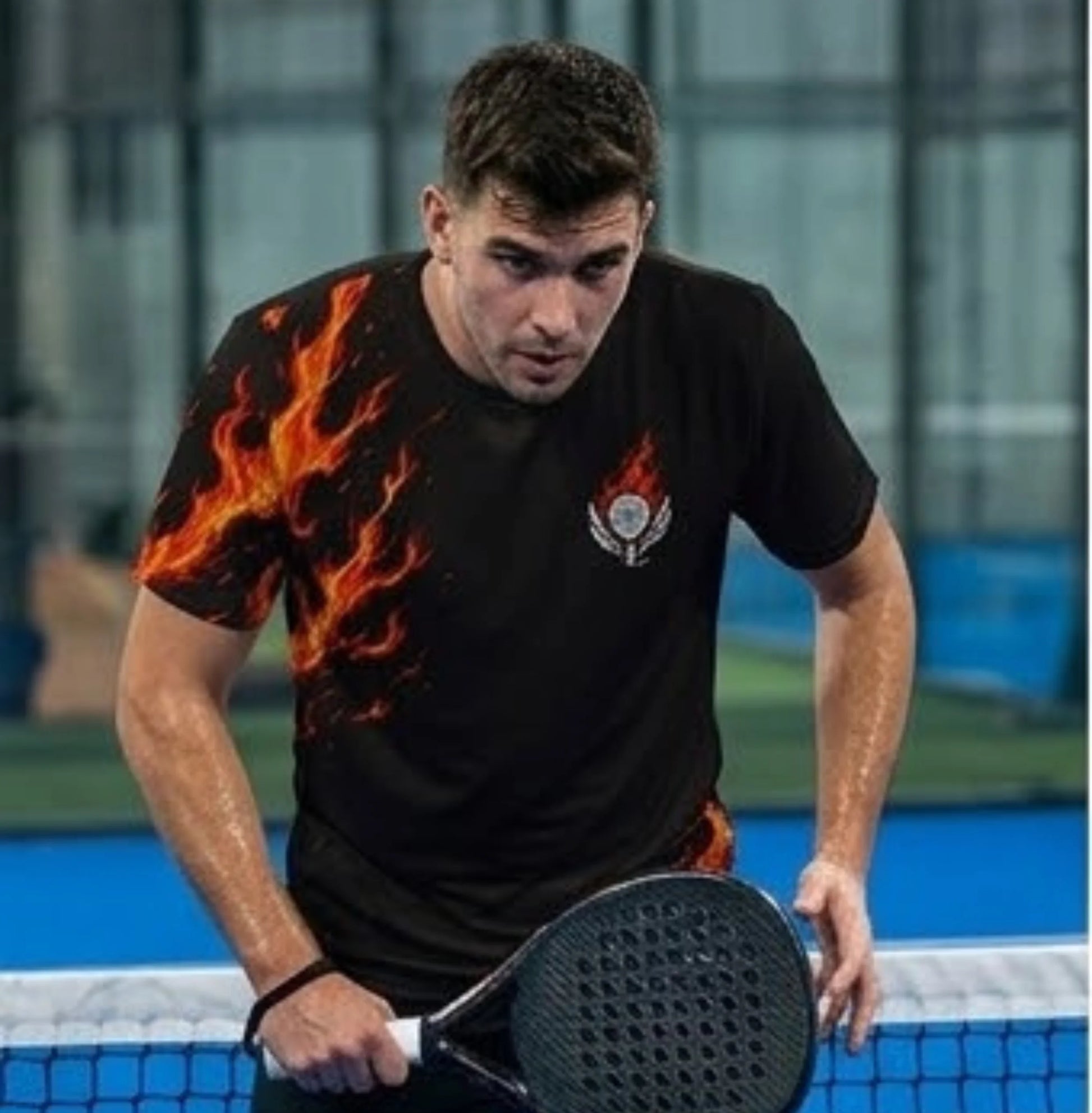 Performance Padel Shirt Man playing paddle tennis on a court with a black t-shirt featuring flame designs.